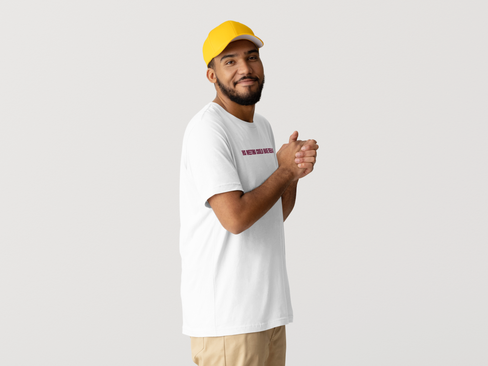 Man wearing a white t-shirt with text and a yellow cap on a light gray background